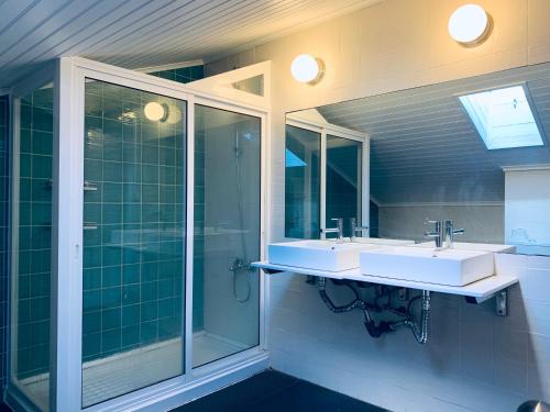 La salle de bains est pourvue de 2 lavabos et d'une douche en verre. dans l'établissement Restelo House Shared Appartment, à Lisbonne