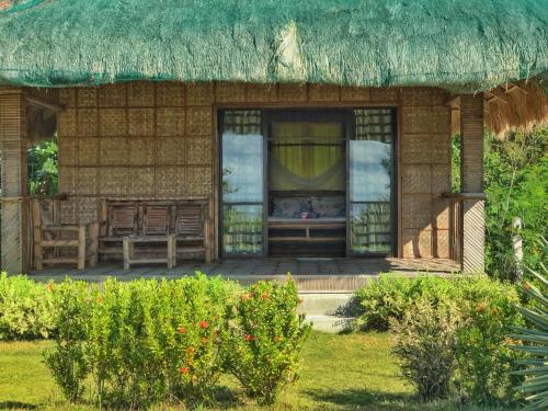 a small house with a thatched roof and a window at Buenavista Paradise Resort in Looc