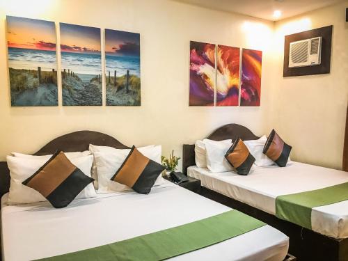 two beds in a room with paintings on the wall at Klir Waterpark Resort and Hotels in Guiguinto