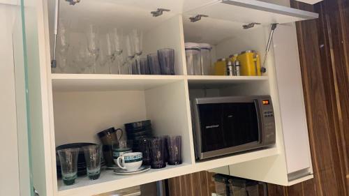 a kitchen cabinet with a microwave and some glasses at STUDIO TOP IDEA INTERLAGOS in Sao Paulo