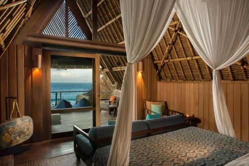 a bedroom with a bed and a view of the ocean at Jeeva Beloam Beach Camp in Tanjung Ringgit