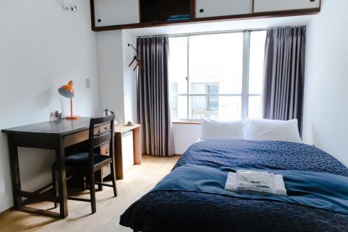 a bedroom with a bed and a desk and a window at Romance za Kado in Atami