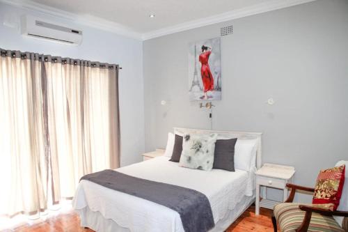a white bedroom with a bed and a chair at LORD WILLIS in Williston