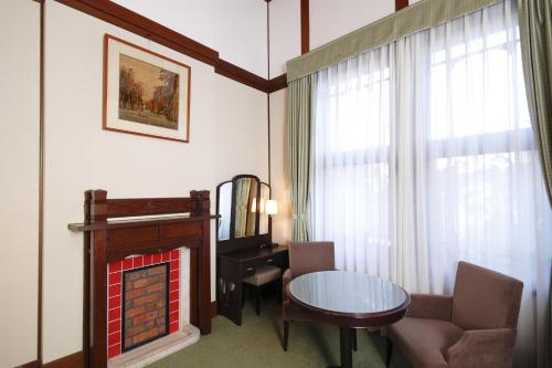 a living room with a fireplace and a table and chair at Nara Hotel in Nara