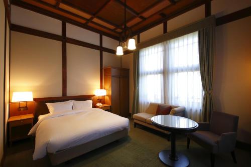 a bedroom with a bed and a chair and a table at Nara Hotel in Nara
