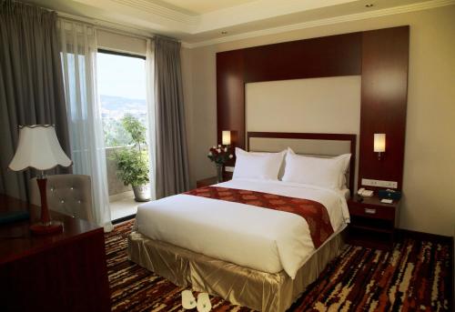 a hotel room with a large bed and a window at Daamat Hotel in Addis Ababa
