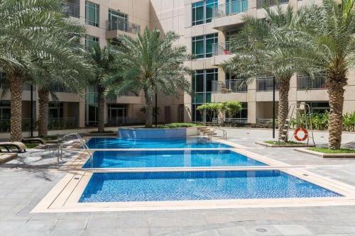 a swimming pool with palm trees in front of a building at Incredible Views at Burj Views Dubai in Dubai