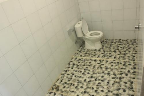 een badkamer met een toilet in een betegelde kamer bij Umah De Arlika UBUD in Ubud