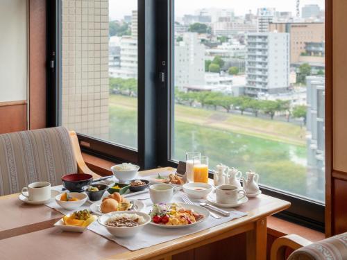 een tafel met ontbijtproducten op een tafel met een raam bij President Hotel Mito in Mito