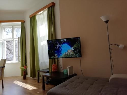 a living room with a couch and a tv on the wall at Anna Apartman in Eger