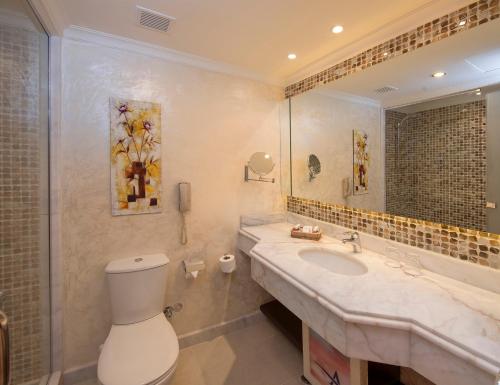 a bathroom with a sink and a toilet and a mirror at Amwaj Oyoun Resort & Casino in Sharm El Sheikh