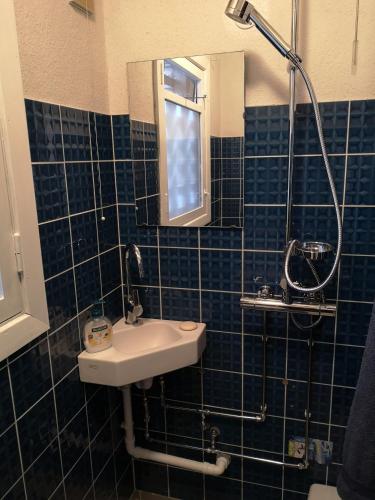 a blue tiled bathroom with a sink and a mirror at Enkeltværelse in Vestervig