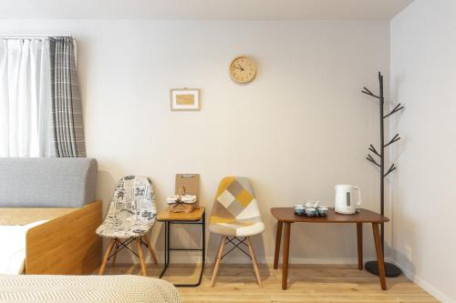 a bedroom with two chairs and two tables and a clock at SAKURA INN Asakusa station walking 4 Min Shinjuku Shibuya Ginza Oshiage in Tokyo