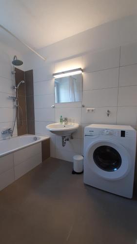 a bathroom with a washing machine and a sink at Gästewohnungen Enztal in Birkenfeld