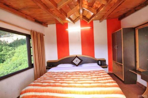 a bedroom with a bed with red and white stripes at Parwati in Nainital