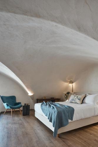 a bedroom with a bed and a blue chair at Winery Hotel 1870 in Fira