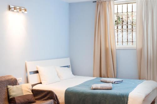 Un dormitorio con una cama y una ventana y una silla. en Cozy Studio "De Shalit", en Herzelia 