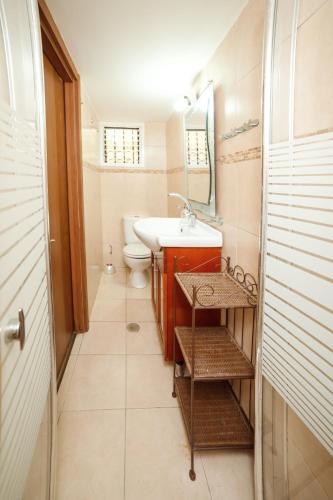 Un baño con lavabo, inodoro y espejo. en Cozy Studio "De Shalit", en Herzelia 