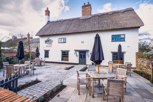 un restaurante con mesas y sombrillas frente a un edificio en The Three Blackbirds en Stetchworth