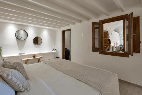 a white bedroom with a bed and a mirror at Winery Hotel 1870 in Fira