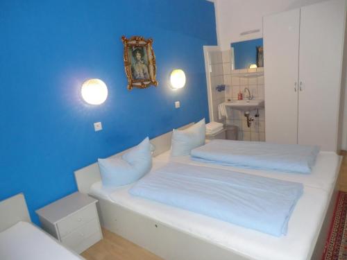 a blue room with two beds and a bathroom at Hotel Pension Haydn in Munich