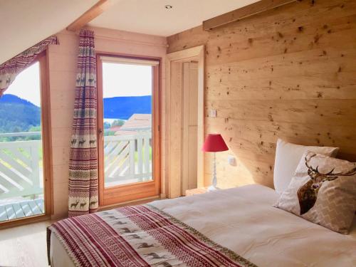 - une chambre avec un lit et une grande fenêtre dans l'établissement Chalet Le Flocon Bleu - Mauselaine avec vue sur le Lac de Gérardmer, à Gérardmer