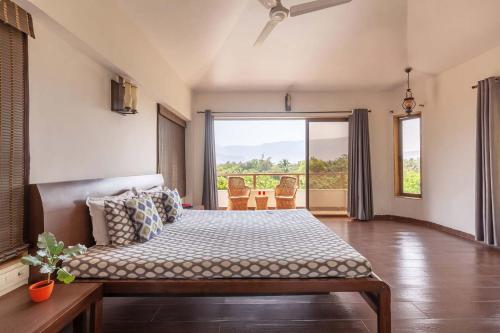 a bedroom with a bed and a large window at StayVista's Santoni Farms - Riverside Bliss with Pool, Orchard & Activities in Karjat