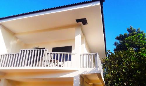 a white building with a balcony and a tree at Adayo Cove Resort in Siquijor