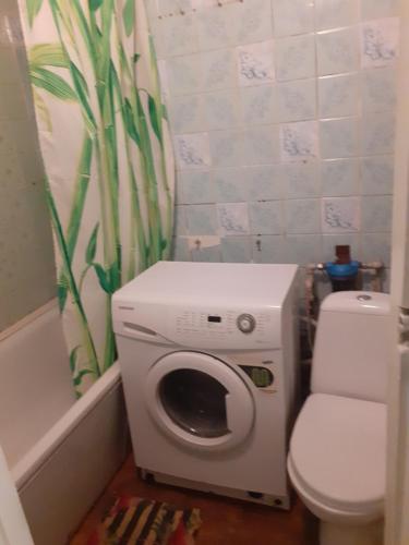 a washing machine in a bathroom next to a toilet at Первомайская. Посуточная уютная квартира in Sumy