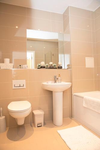 a bathroom with a sink and a toilet and a mirror at Sunshine Place in Enfield