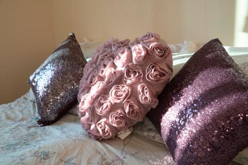 a bed with pink roses and sequin pillows at Tranquil Apartment with Stunning Views in Enfield