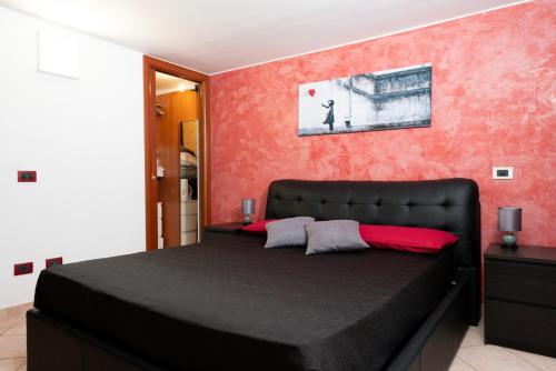 a bedroom with a black bed and a red wall at The Roof - Appartamento con terrazza al centro di Civitavecchia in Civitavecchia