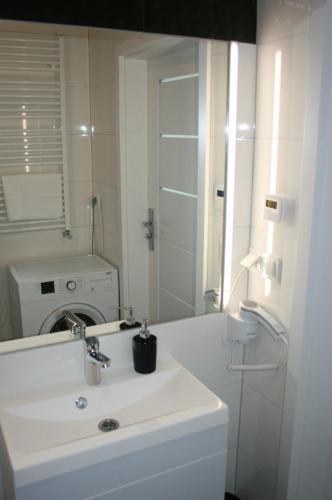 a white bathroom with a sink and a mirror at Apartament Miedzianka II in Polkowice