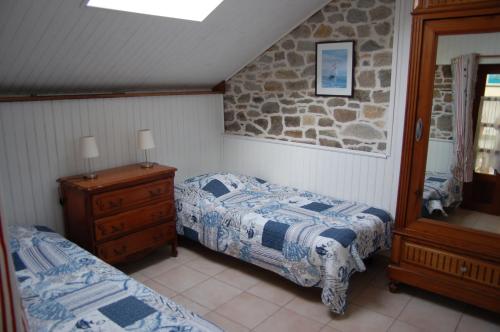 1 dormitorio con 2 camas y pared de piedra en gîte marin petit châtelet, en Hirel