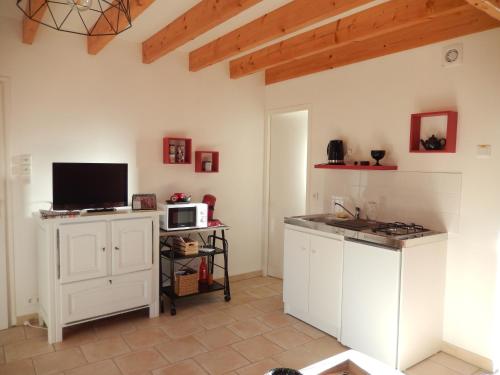 a kitchen with white cabinets and a tv on the wall at Studio Appart' Les jards in Bressuire