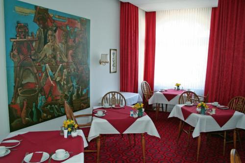 ein Esszimmer mit 2 Tischen und roten Tischdecken in der Unterkunft Hotel Fernblick in Bad Harzburg