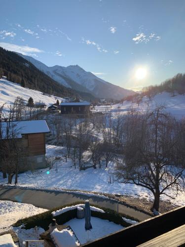a view of a snow covered field with the sun setting at Hotel Haus Mühlebach in Ernen