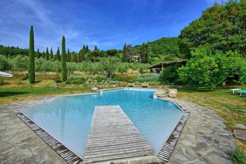 a swimming pool in a garden with a wooden dock at Agriturismo Fattoria Celle in Figline Valdarno