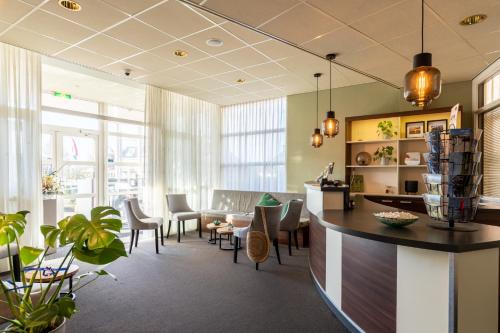 un hall de bureau avec un bar, des chaises et des tables dans l'établissement Hotel Ameland, à Nes