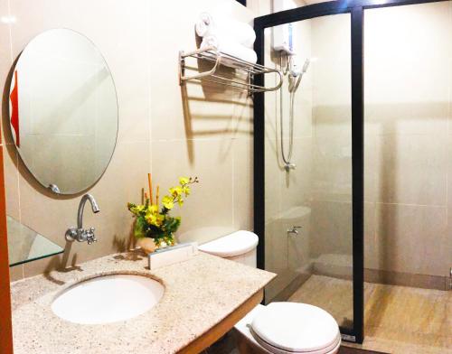 a bathroom with a sink and a toilet and a mirror at Klir Waterpark Resort and Hotels in Guiguinto