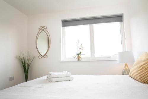 a white bedroom with a white bed with a mirror at Sunshine Place in Enfield