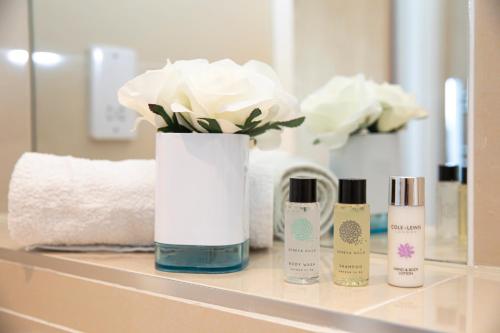a bathroom counter with a vase of flowers and cosmetics at Sunshine Place in Enfield