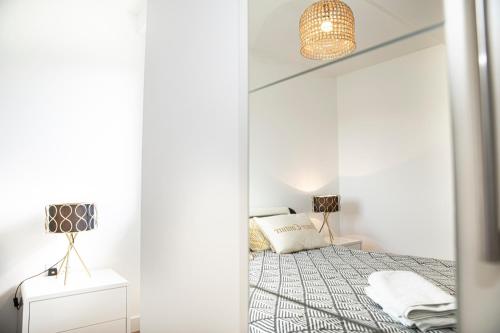 a white bedroom with a bed and a lamp at Sunshine Place in Enfield