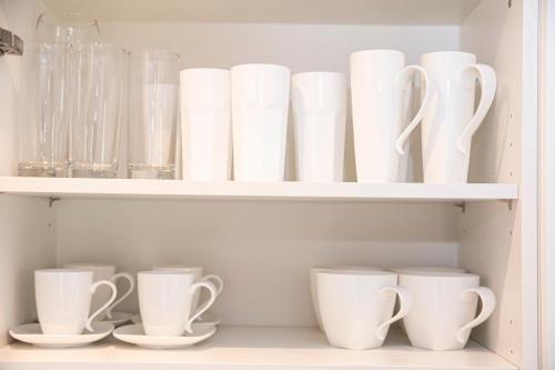 a shelf filled with white cups and vases at Sunshine Place in Enfield