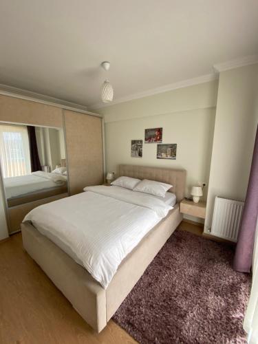 a bedroom with a large white bed and a mirror at Dora City Apartament in Cluj-Napoca