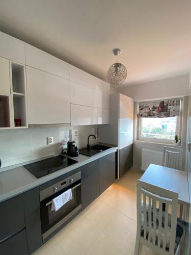 a kitchen with white cabinets and a sink and a table at Dora City Apartament in Cluj-Napoca