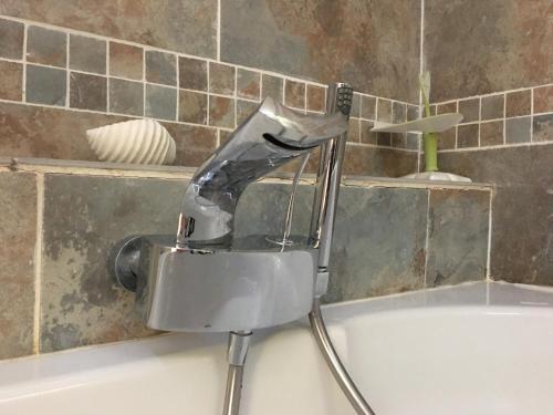 a faucet on a bath tub in a bathroom at T2 climatisé baignoire terrasse Jacuzzi Piscine Sauna in Launaguet