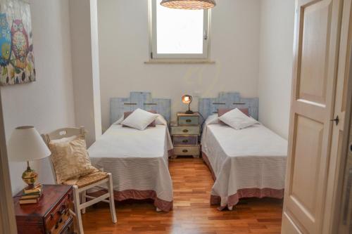 ポリニャーノ・ア・マーレにあるTrulli&Dimore - Villa Caterinaのベッド2台、椅子、窓が備わる客室です。