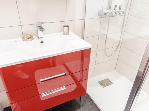 La salle de bains est pourvue d'un lavabo rouge et d'une douche. dans l'établissement les appartements du 10, à Rochefort