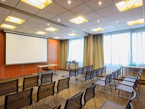 a conference room with chairs and a white screen at Novotel Paris Créteil Le Lac in Créteil